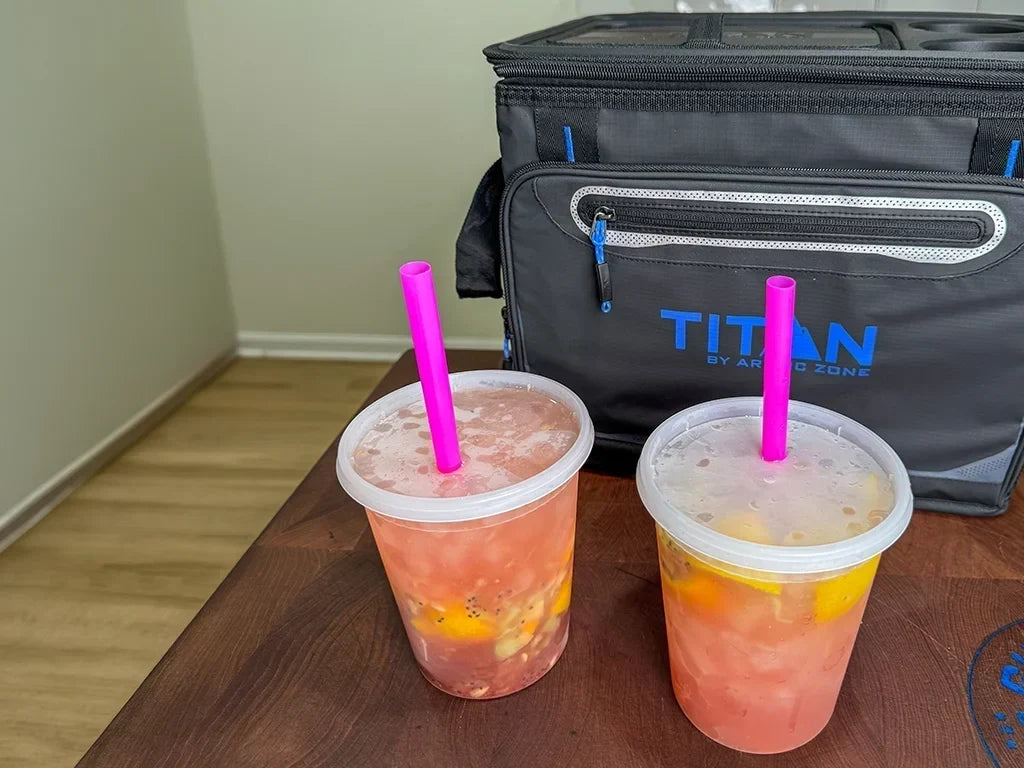Two cups of strawberry lemonade next to a Titan collapsible tabletop cooler.