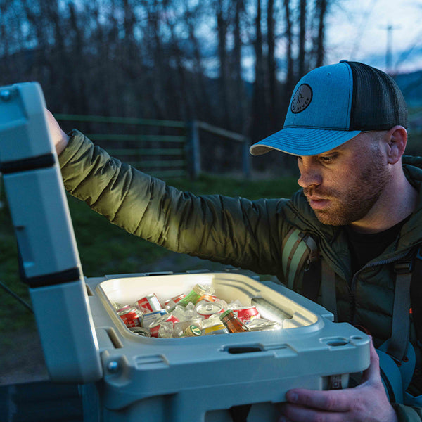 Guy looking into a Titan PRO Roto Hard Cooler filled with cans and ice