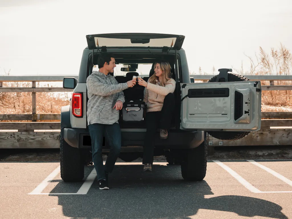 Two people enjoying a beverage out of their Titan Cooler while on a road trip