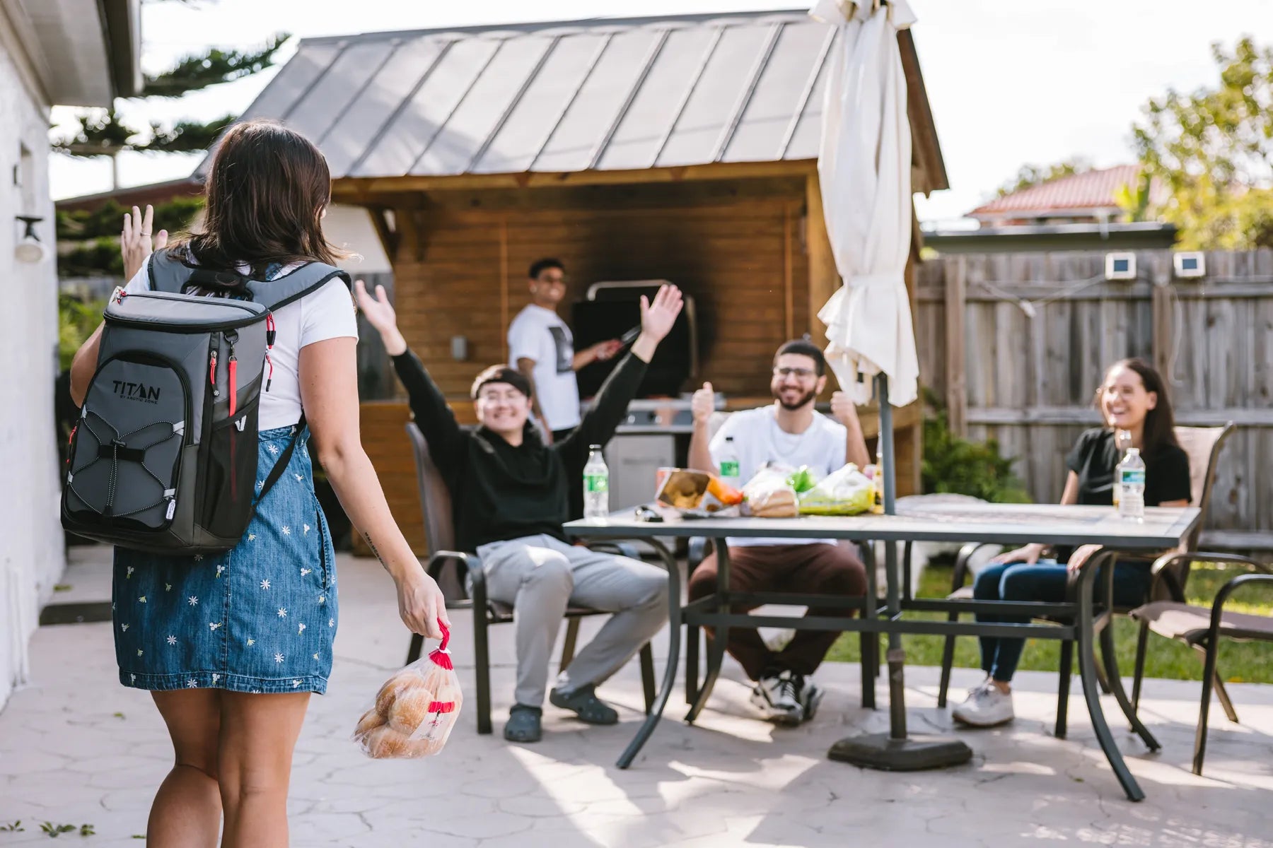 Girl wearing a Titan Eco 24 Can Backpack Cooler arriving to a backyard party