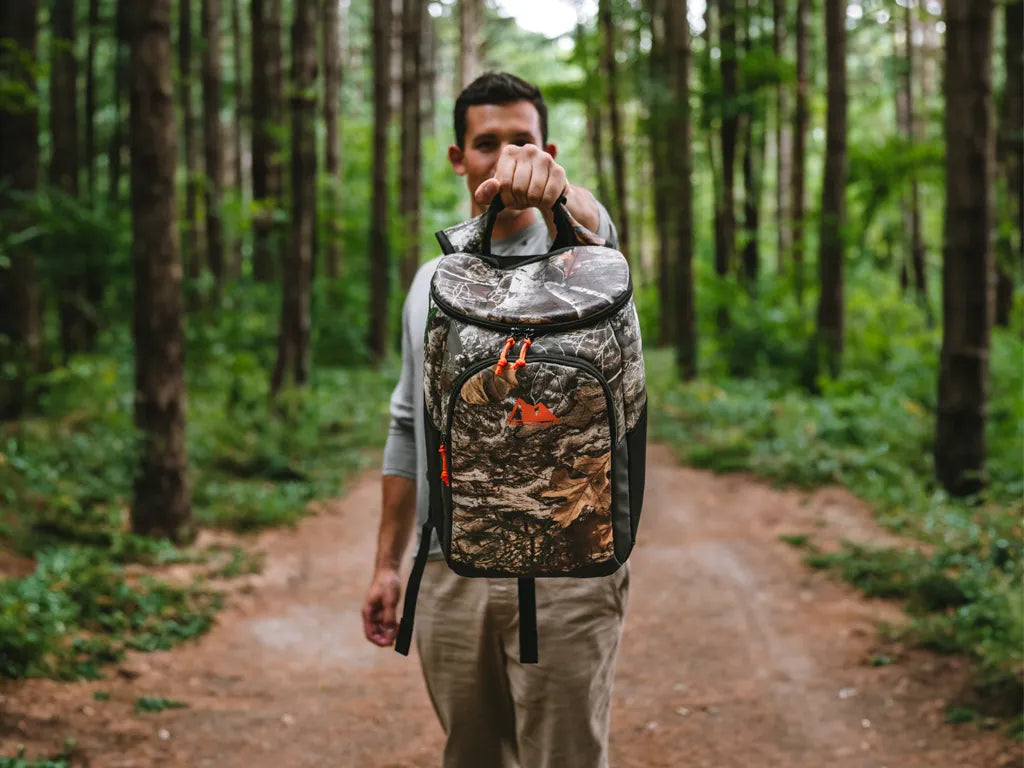 Man holding up an Arctic Zone Realtree Backpack Cooler in a forest