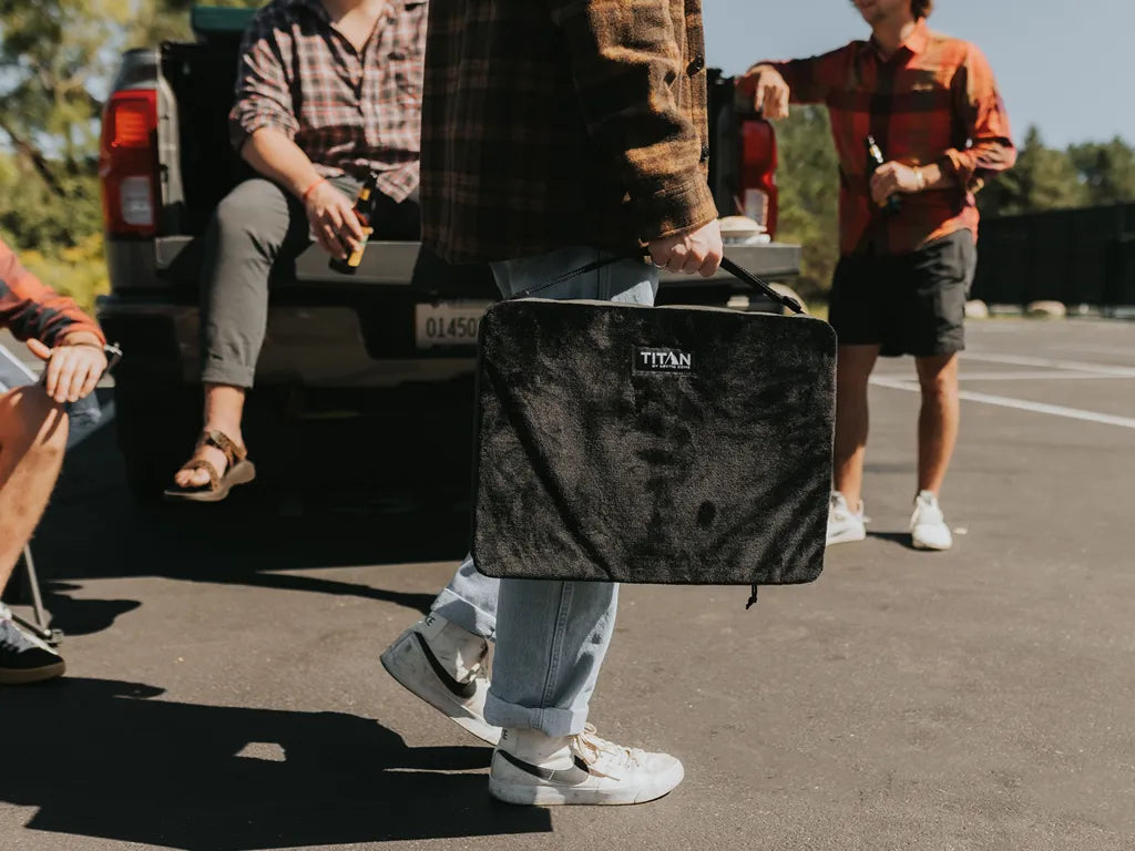 Guy carrying a Titan Temperature Controlled Heatable Seat cushion while at a tailgate party