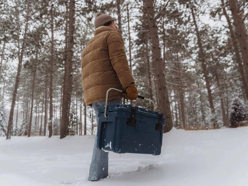 Person holding a hard cooler in a forest