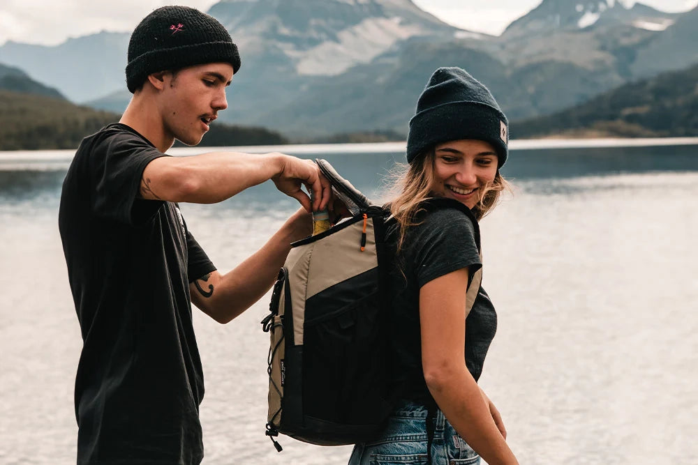 Girl wearing a Titan backpack cooler while guy reaches in to grab a cold drink