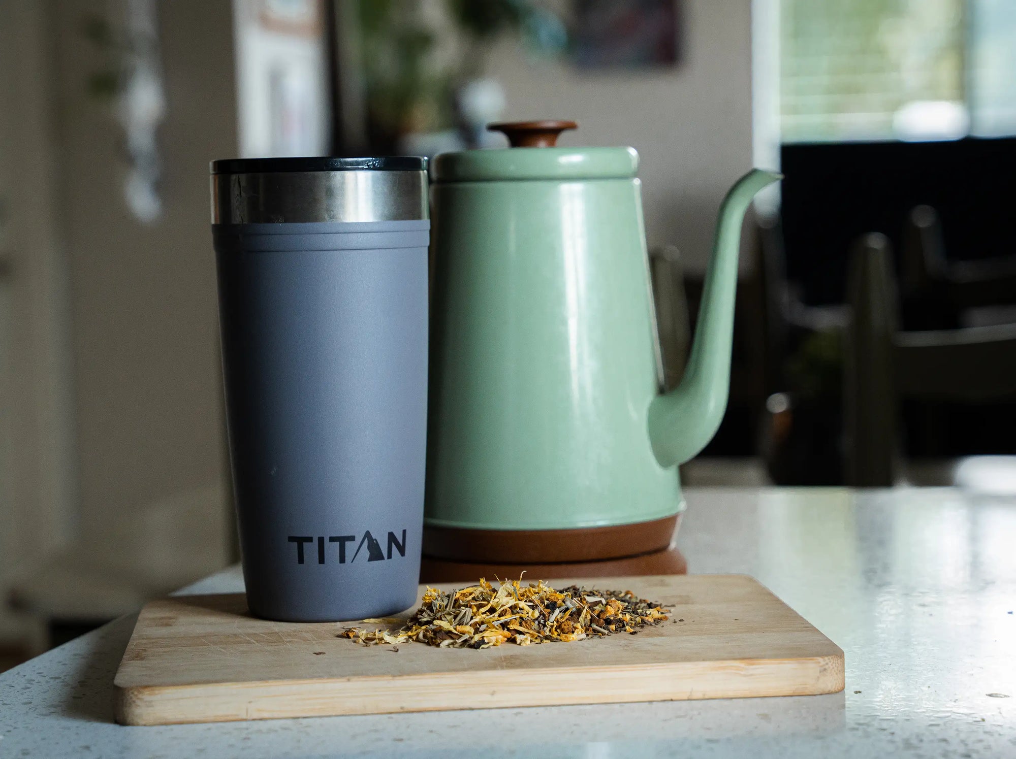 Titan 20 oz Tumbler next to loose leaf and a kettle on a kitchen counter