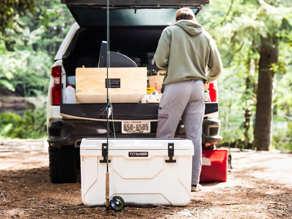 Person with a Titan PRO 55Q Rotomolded Hard Cooler next to their vehicle, getting ready to go fishing