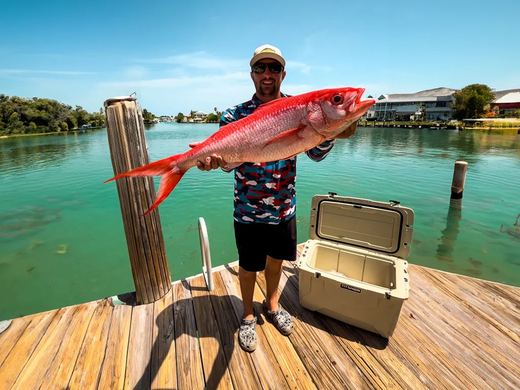 Man holding a big fish next to a Titan PRO roto hard cooler