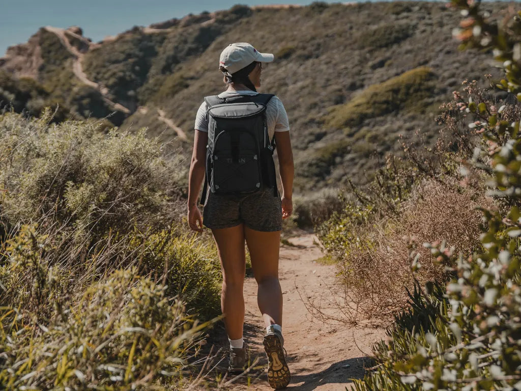 Girl hiking while wearing a backpack cooler