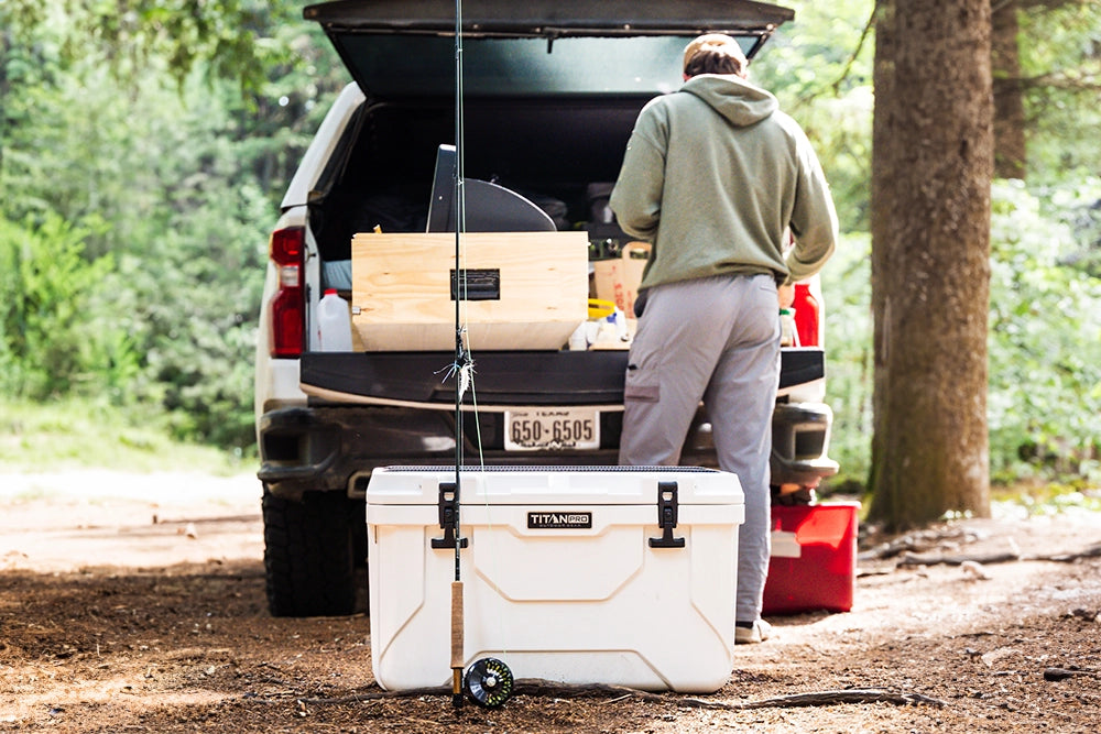 Person with a Titan PRO 55Q Rotomolded Hard Cooler next to their vehicle, getting ready to go fishing