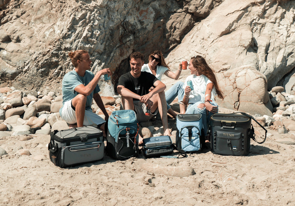 Four friends sitting together at the beach with an variety of Arctic Zone coolers