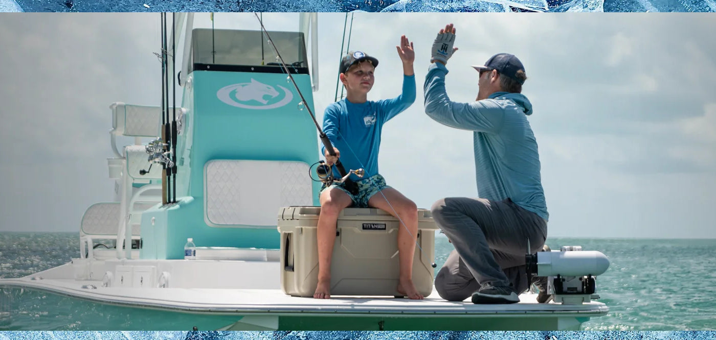 Father and son beside a hard cooler while fishing on a boat