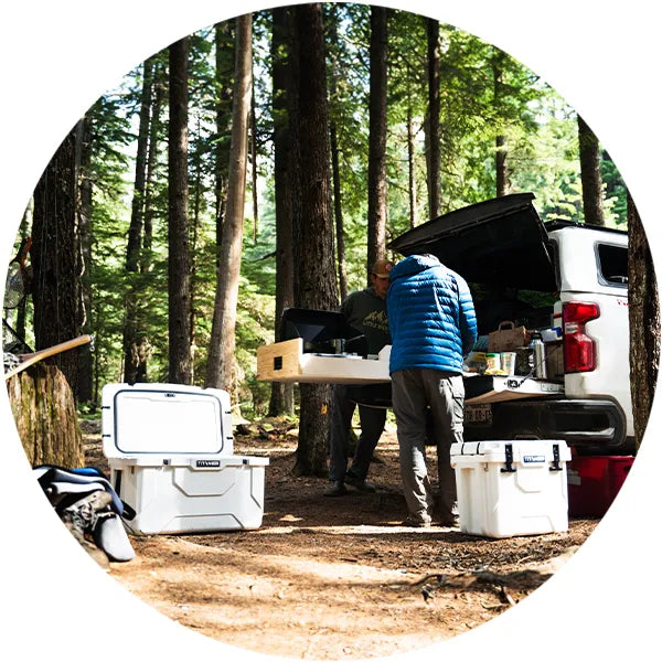 Two men prepping a meal while camping in the wild