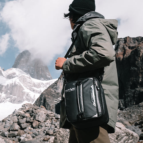 A man carrying his Titan lunch bag while in the enjoying an adventure in the mountains