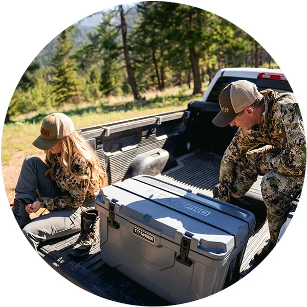 Two people in camo next to a Titan PRO Hard Cooler