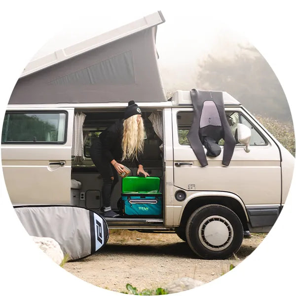 Lady grabbing food from a Titan Zipperless Cooler while in a camper van