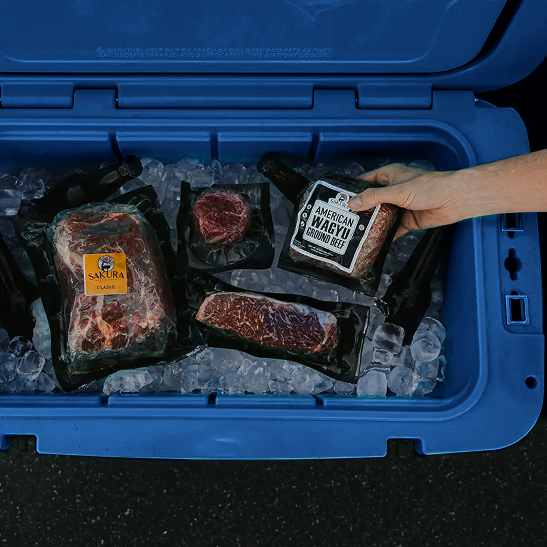 Person pulling out frozen meat from a 55Q Hard Cooler