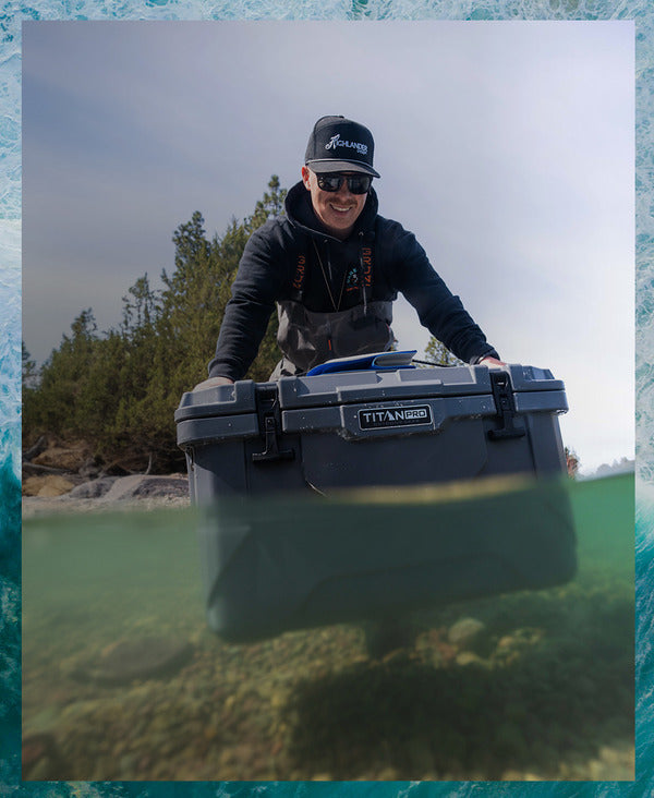 Guy carrying a Titan PRO 55Q Roto Hard Cooler in a lake