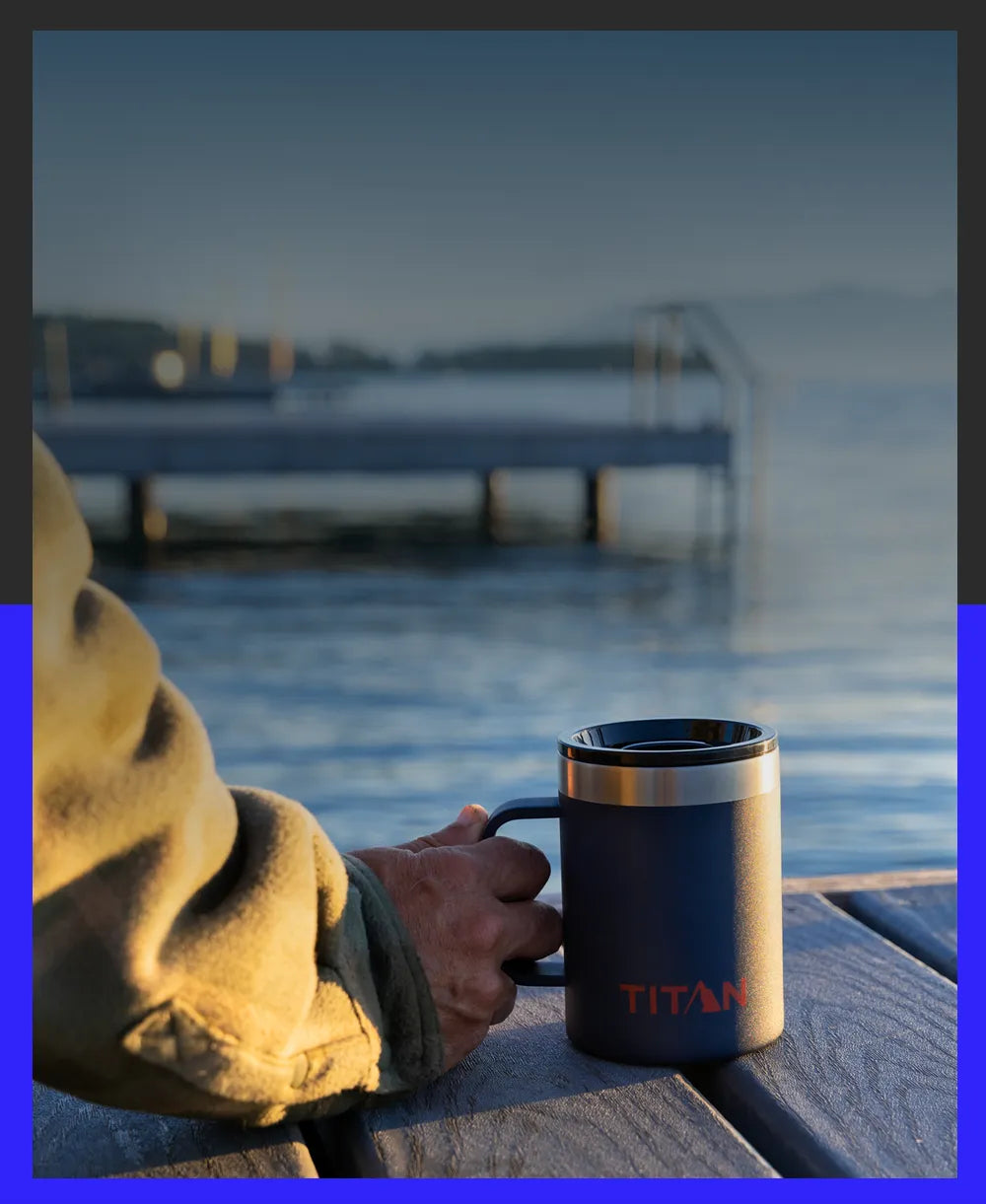 Person holding a Titan by Arctic Zone 14 Oz Stainless Steel Mug while sitting on a dock, watching the sunset